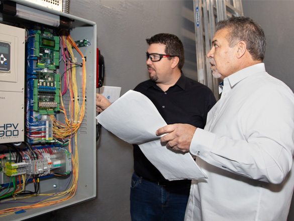 two elevator specialists consulting a plan while assessing elevator equipment